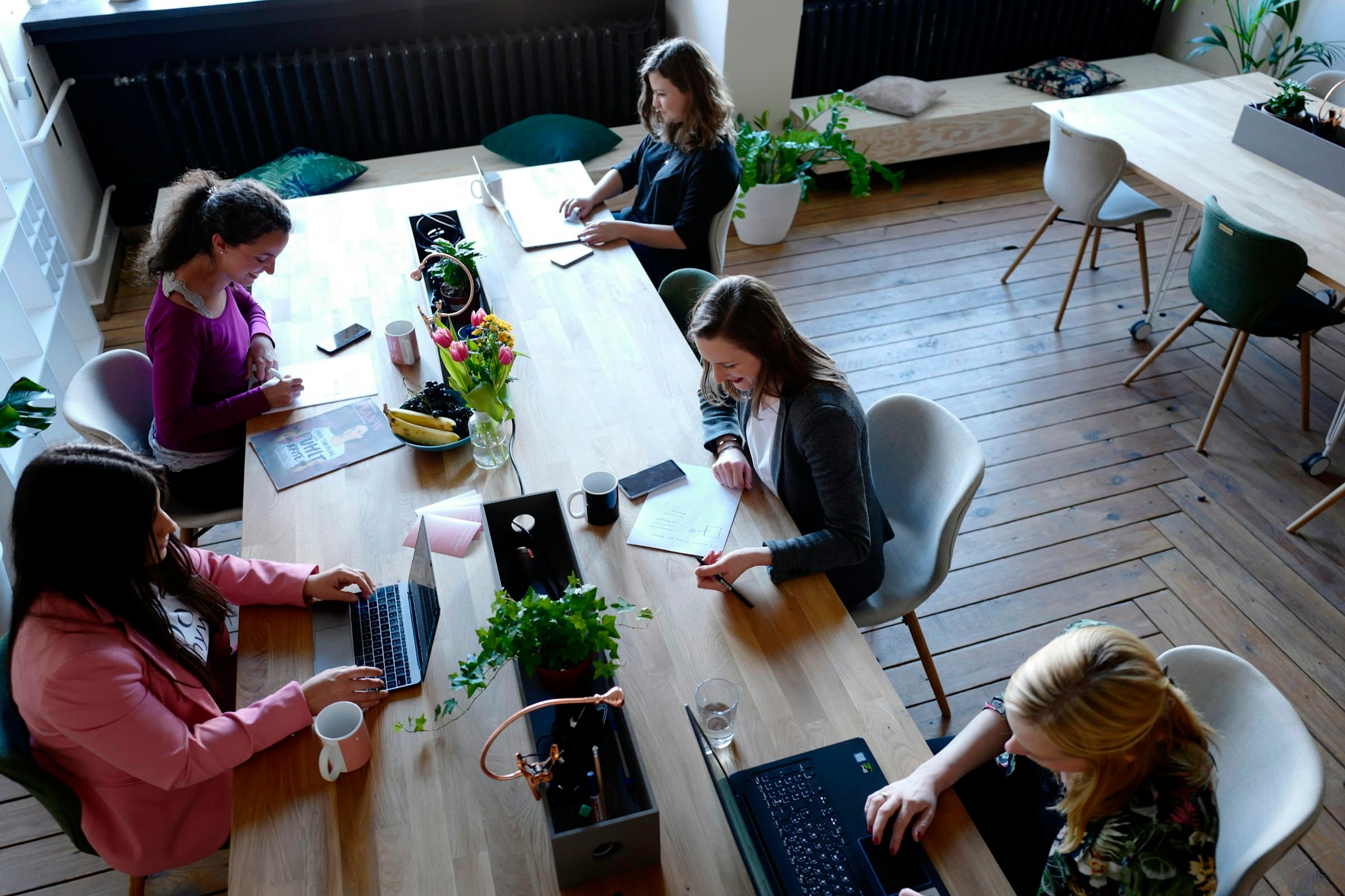 Five colleagues at a long wooden table seen from above